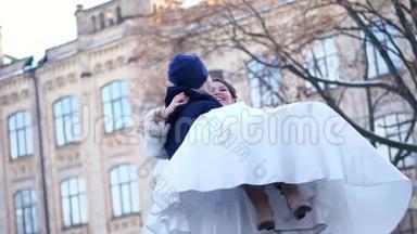 冬季婚礼。 新婚夫妇穿着婚纱。 新郎把新娘抱在怀里，旋转着。 他们开心，微笑着